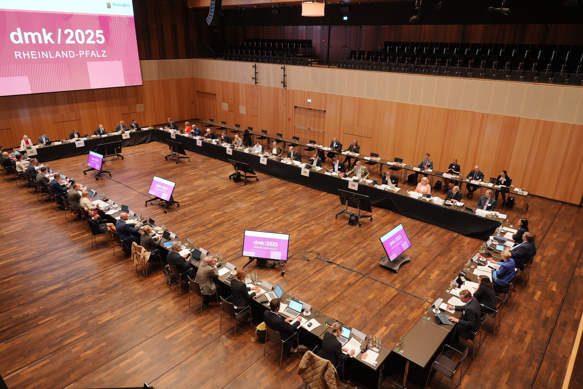 Blick von oben auf die Teilnehmerinnen und Teilnehmer der Digitalministerkonferenz an ihren Tischen.