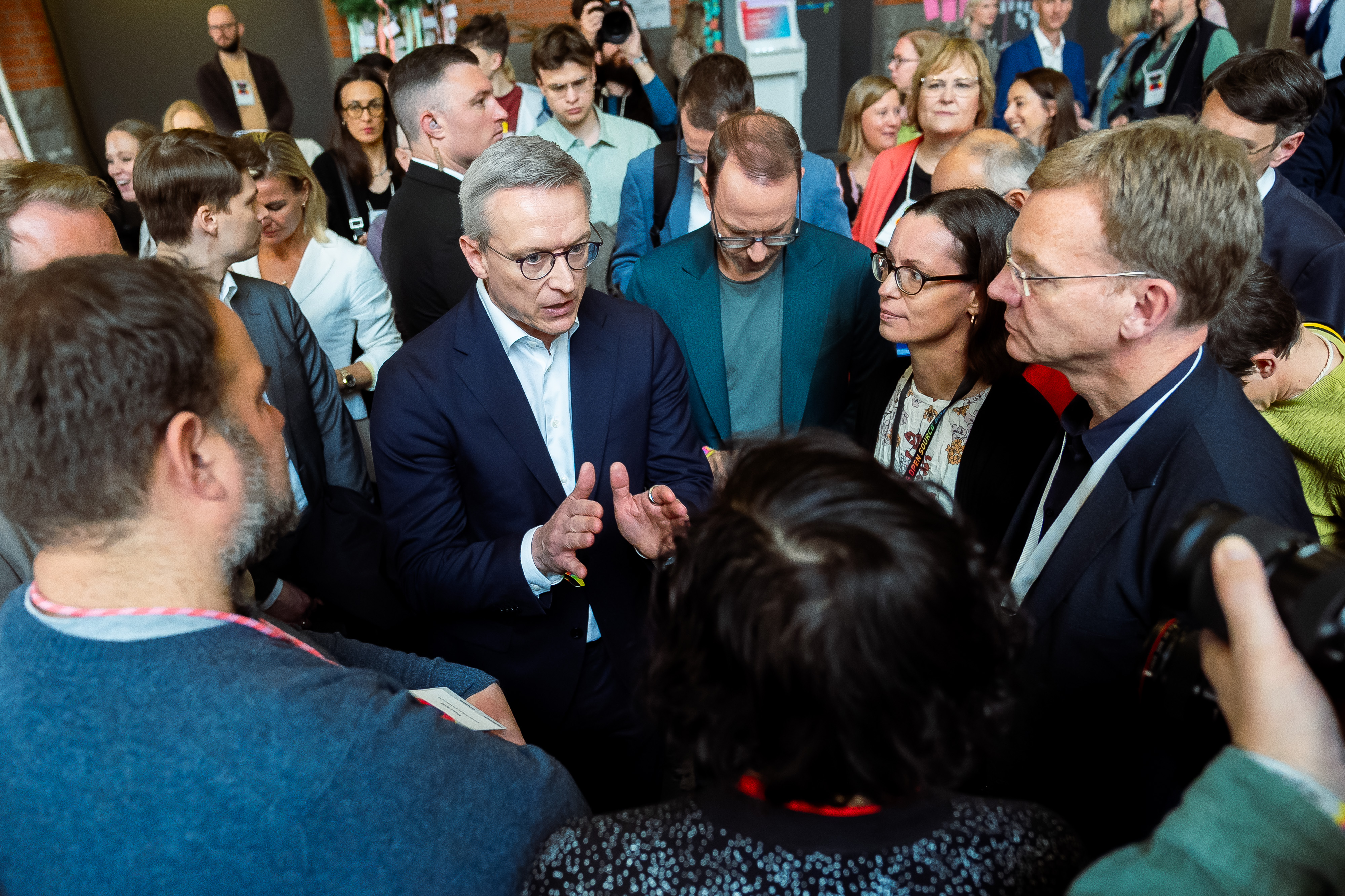 Bundesdigitalminister Dr. Karsten Wildberger ist umringt von Personen auf dem Messegelände