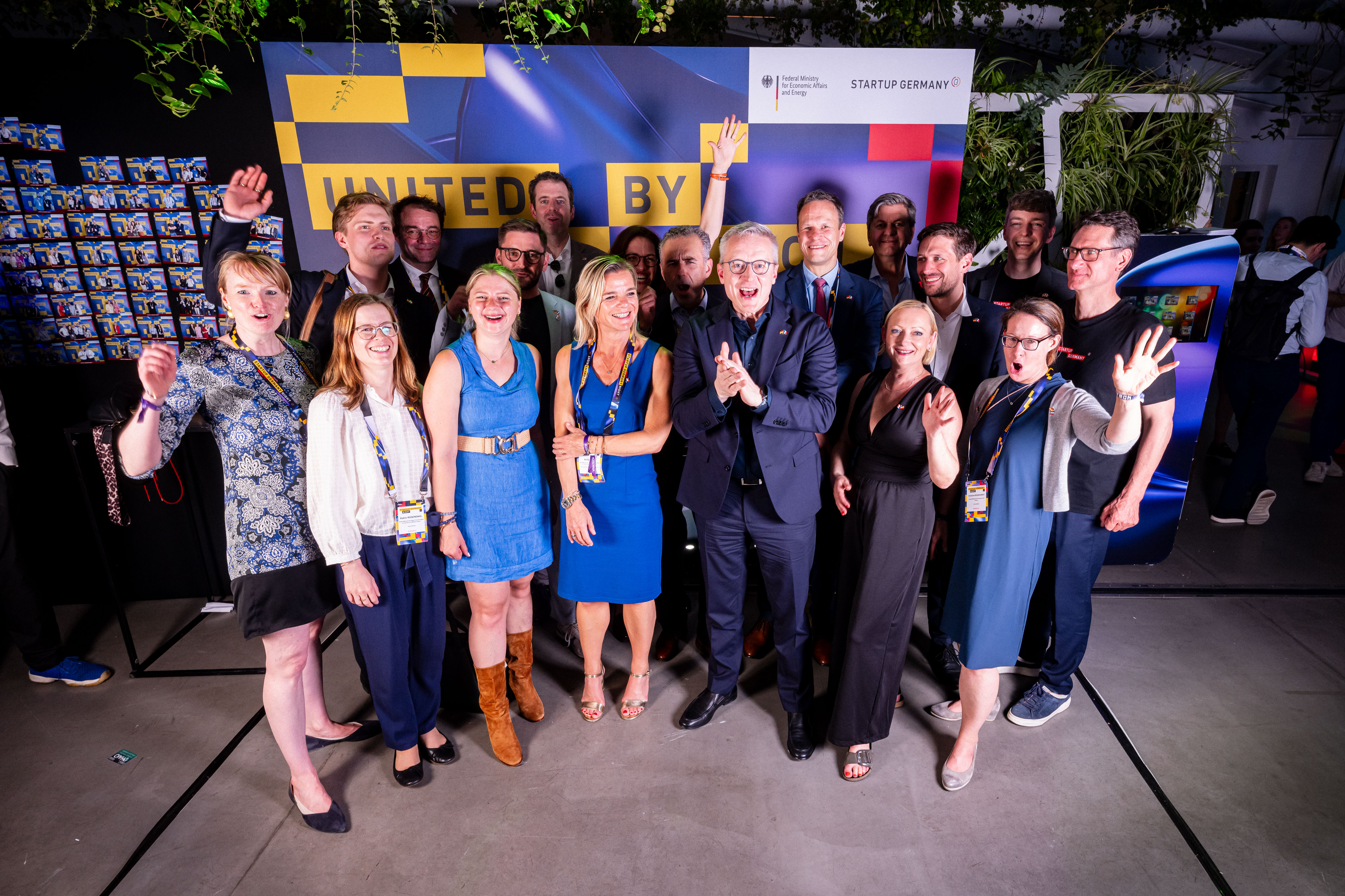Eine Gruppe teils jubelnder Personen beim Gruppenbild vor der Startup-Germany-Pressewand. 