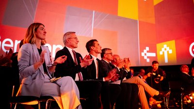 Karsten Wildberger, Arthur Mensch, Florian Herrmann, Fabian Mehring und weitere Personen sitzen in einem Festsaal und klatschen in die Hände.