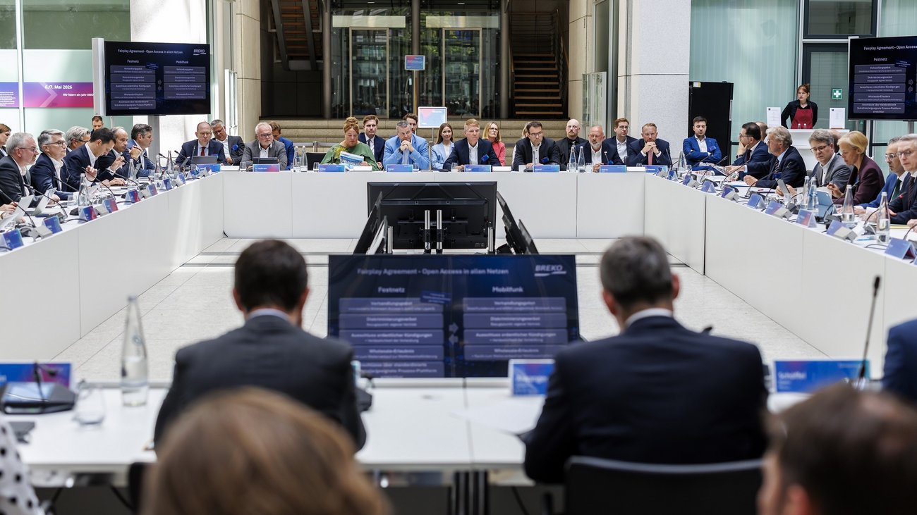 Blick auf Teilnehmende der Veranstaltung an einem rechteckig angeordneten Rednertisch