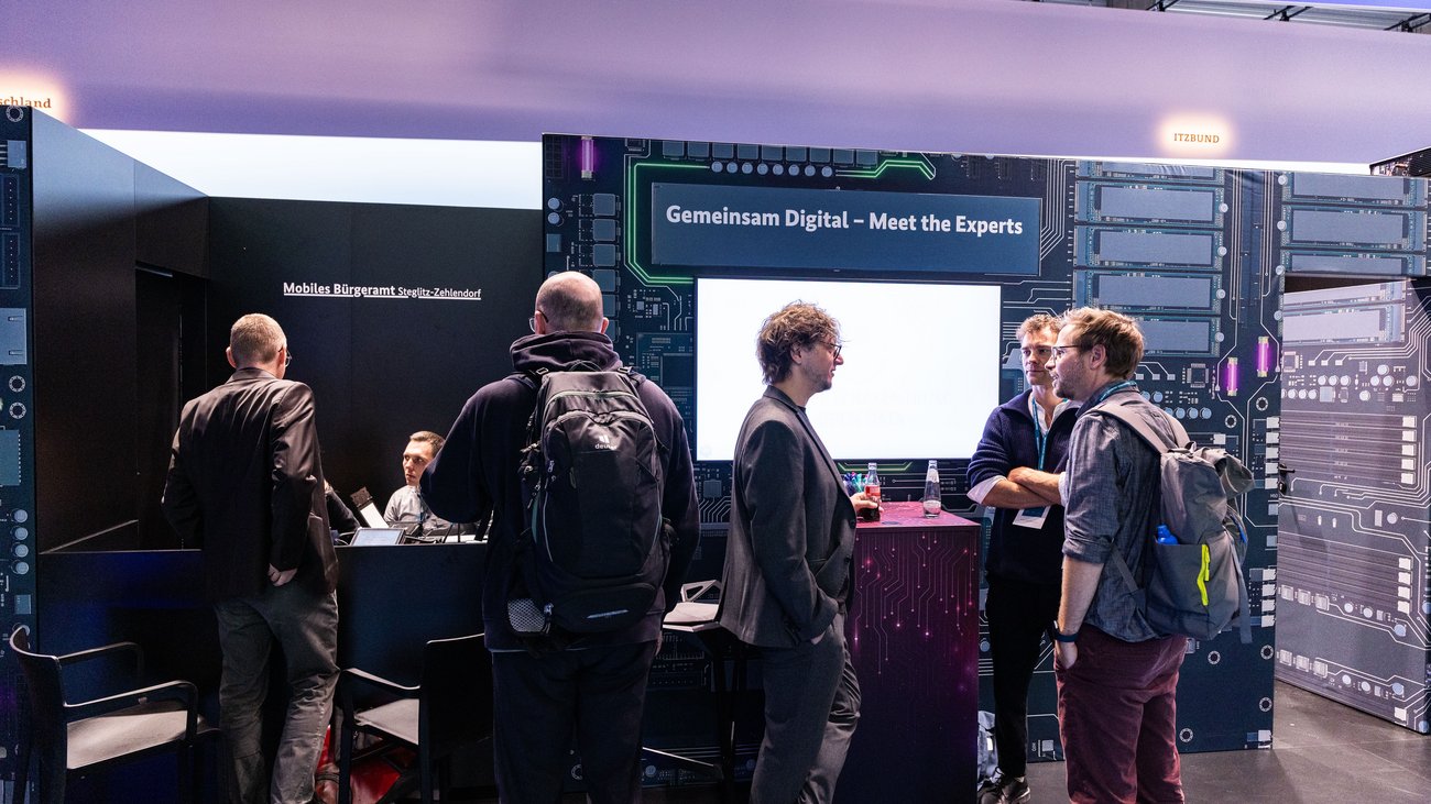 Situation an einem Counter am Messestand, im Hintergrund liest man "Mobiles Bürgeramt Steglitz-Zehlendorf". 