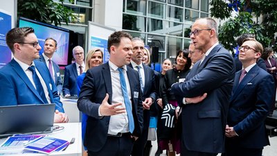 Maximilian Wehage unterhält sich mit Friedrich Merz. Hinter ihnen Karsten Wildberger, Thomas Jarzombek und Philipp Amthor sowie weitere Personen.