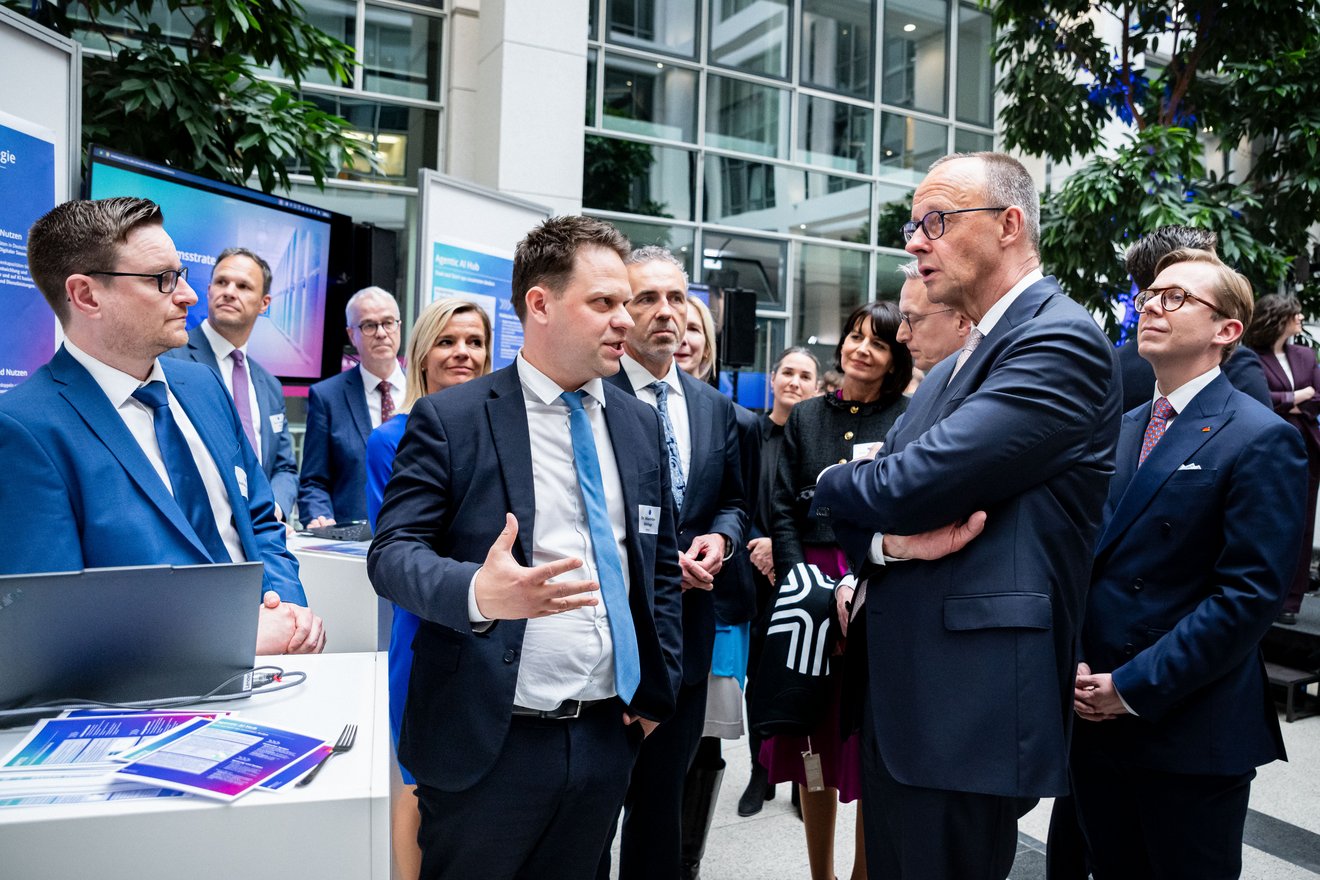 Maximilian Wehage unterhält sich mit Friedrich Merz. Hinter ihnen Karsten Wildberger, Thomas Jarzombek und Philipp Amthor sowie weitere Personen.