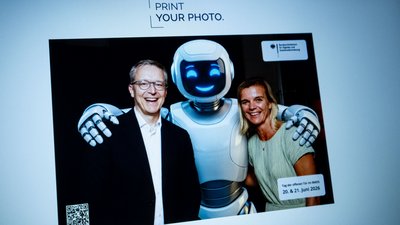 Minister Wildberger und Betty Kieß mit einem weißen Roboter auf einem mit KI erstellten Foto