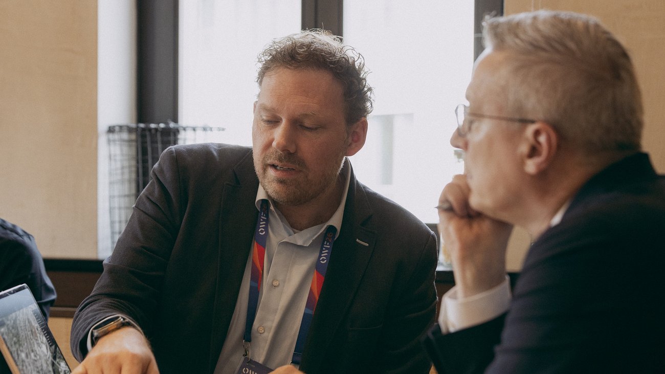 Zwei Männer sitzen in einem Besprechungsraum und sind im Gespräch.