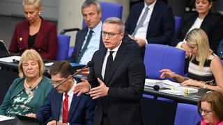 Blick auf die Regierungsbank im Bundestag. Ein Minister steht und redet in ein Mikrofon. 