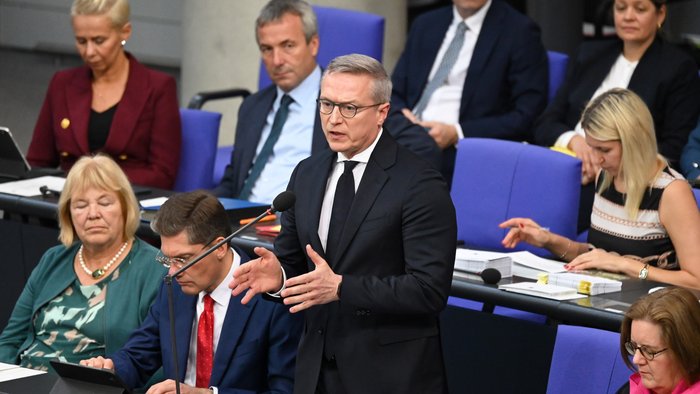 Blick auf die Regierungsbank im Bundestag. Ein Minister steht und redet in ein Mikrofon. 