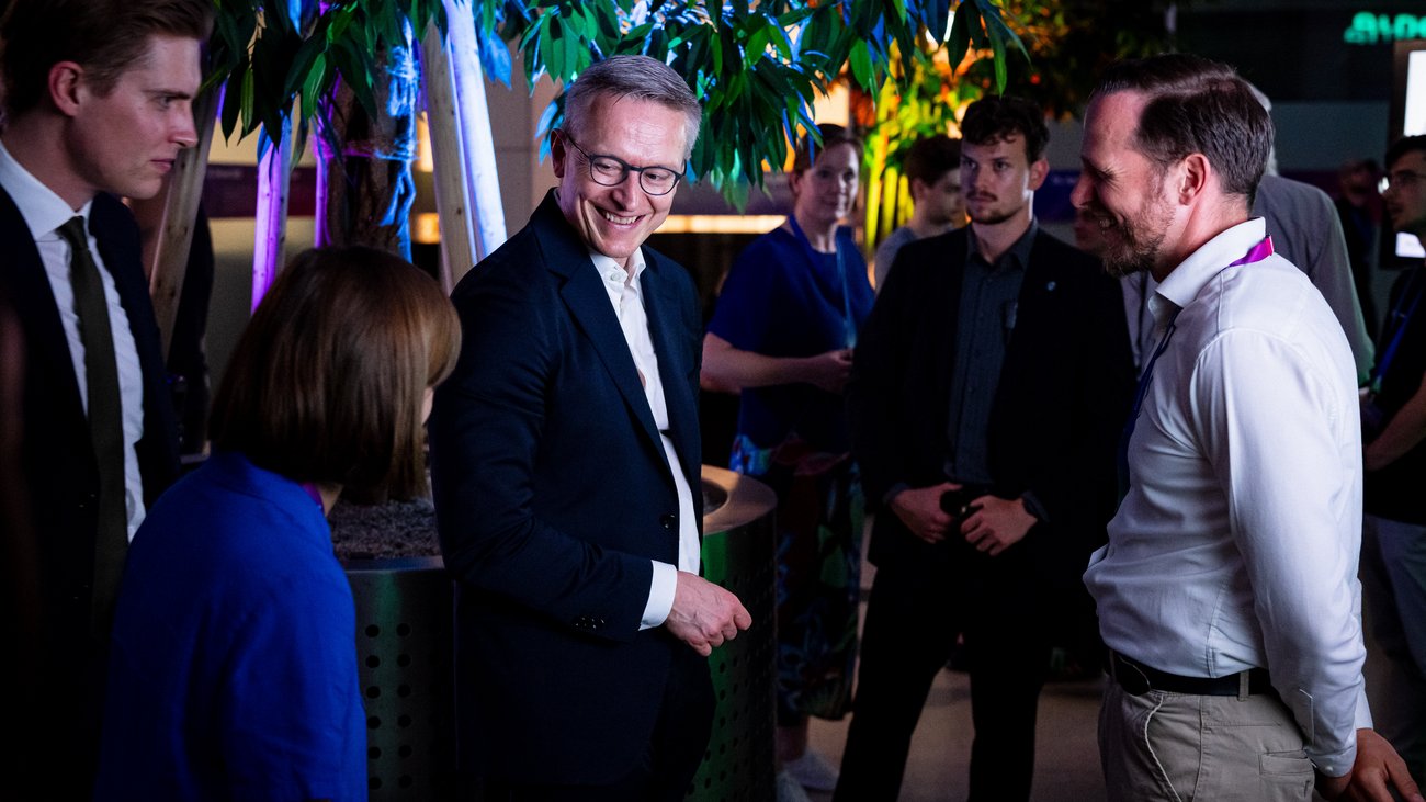 Minister Wildberger steht mit mehreren Personen zusammen und lächelt