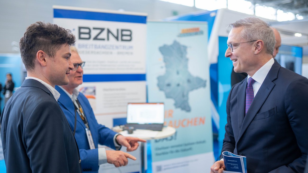 Bundesdigitalminister Dr. Karsten Wildberger und weitere Personen an einem Messestand der ANGA COM