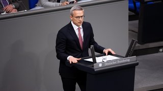 Dr. Karsten Wildberger steht im dunklen Anzug im Bundestag und hält eine Rede.