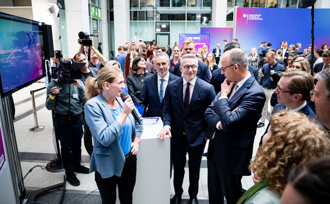 Claudia Straub spricht in ein Mikrofon, neben ihr stehen Friedrich Merz, Karsten Wildberger und Thomas Jarzombek. Im Hintergrund sind weitere Personen zu sehen.