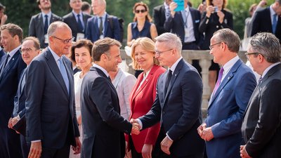 Bundesdigitalminister Karsten Wildberger begrüßt Frankreichs Präsidenten Emmanuel Macron geben sich die Hand. Um sie herum stehen weitere Mitglieder der Delegationen und Gäste.