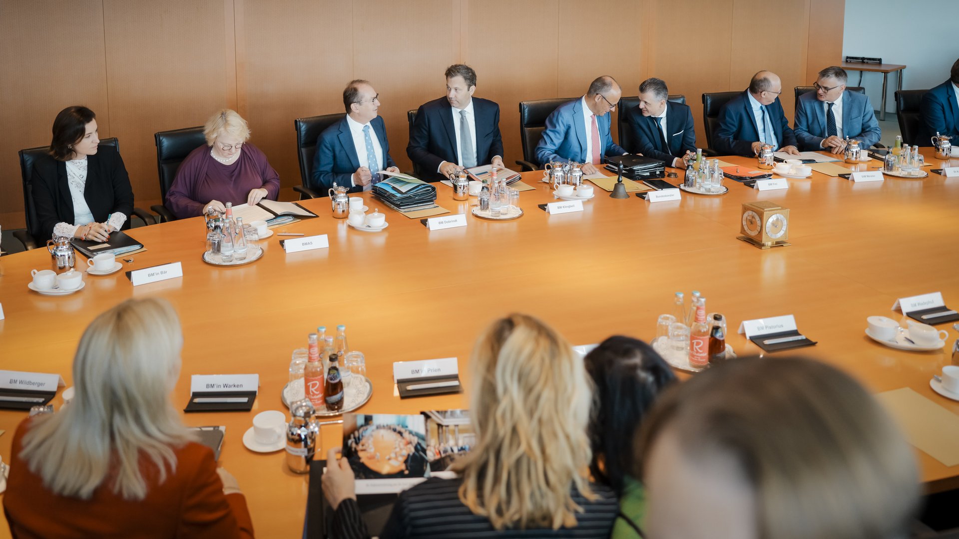 Blick in die Kabinettssitzung: Viele Männer und Frauen in Business-Kleidung sitzen am runden Kabinettstisch. 