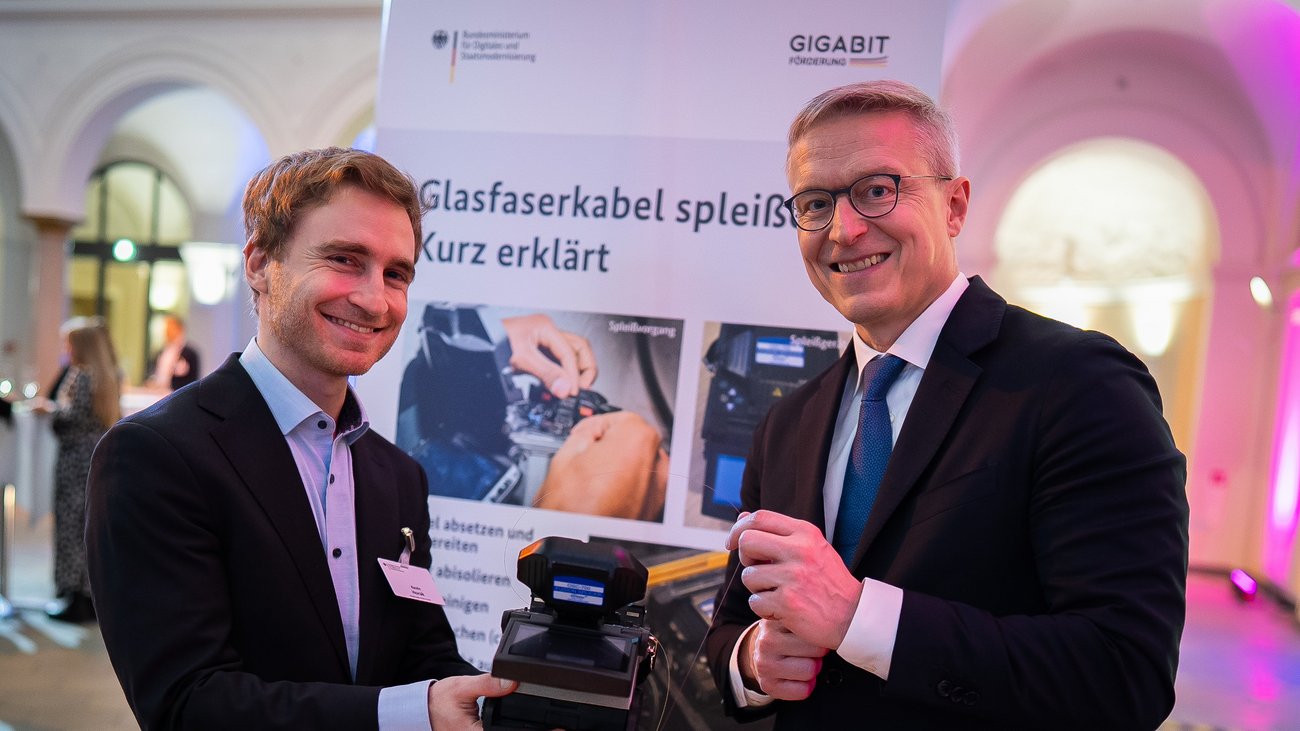 Bundesminister Dr. Karsten Wildberger hält seine erste erfolgreich gespleißte Glasfaser in den Händen