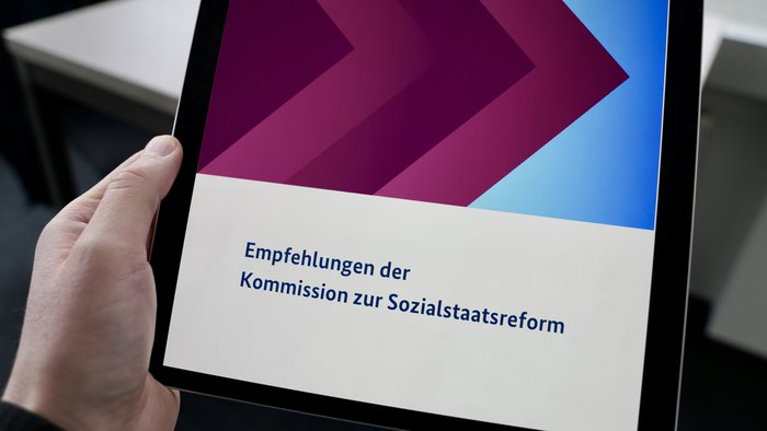 Hand hält ipad, darauf ist der Abschlussbericht Sozialstaatsreform