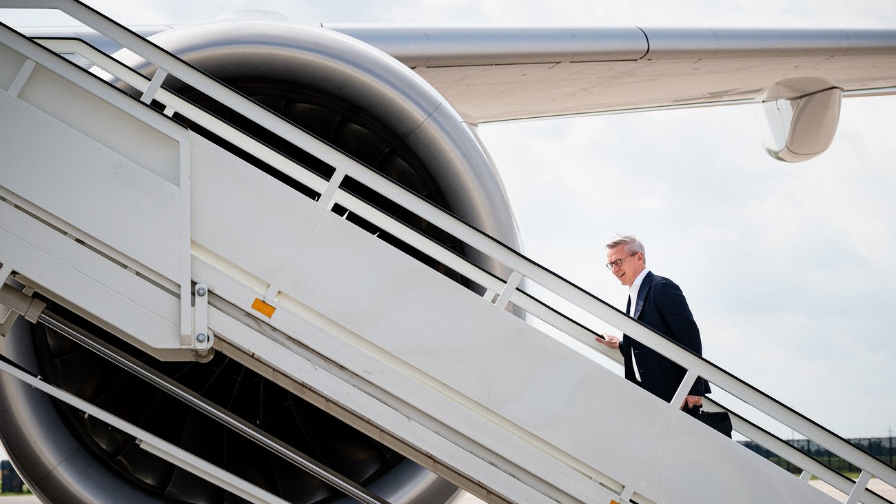Karsten Wildberger steigt über eine Treppe hinauf in ein Flugzeug.