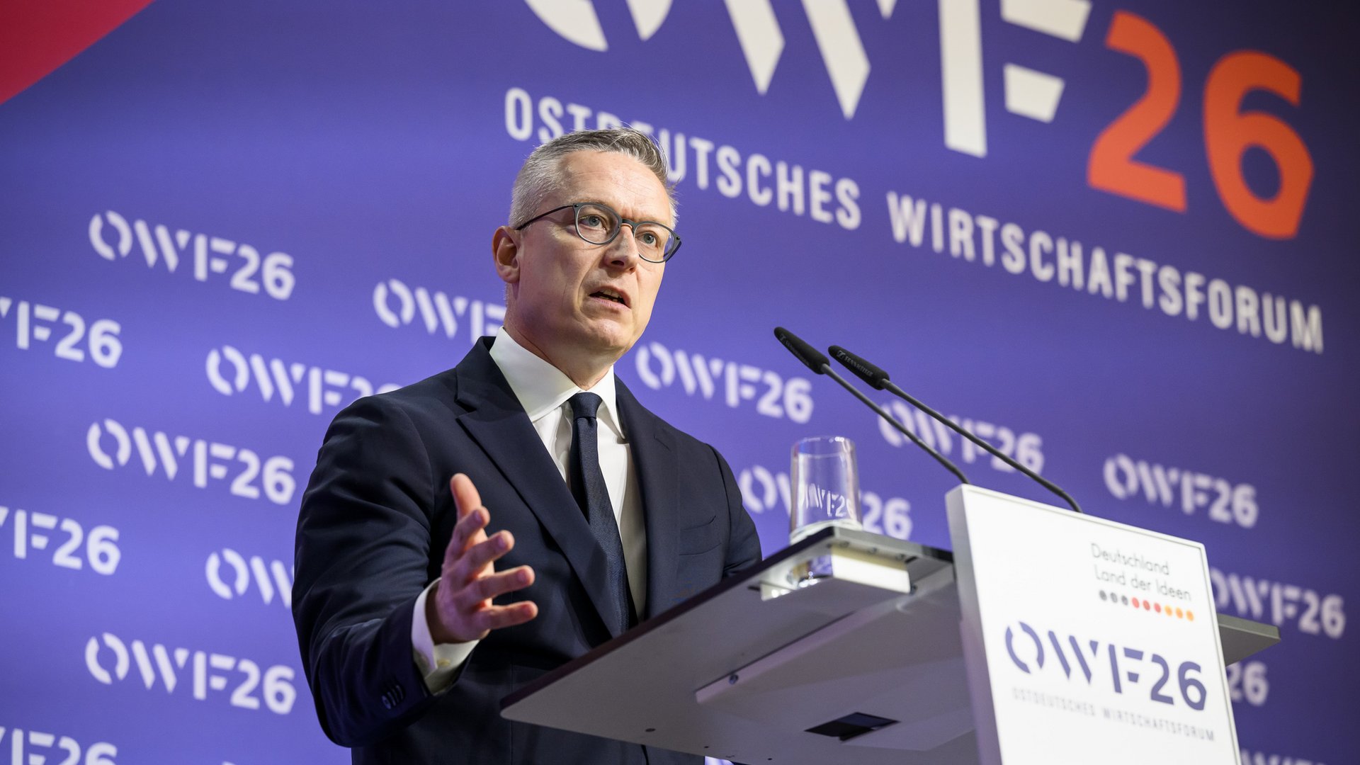 Karsten Wildberger steht an einem Rednerpult und spricht ins Mikrofon.