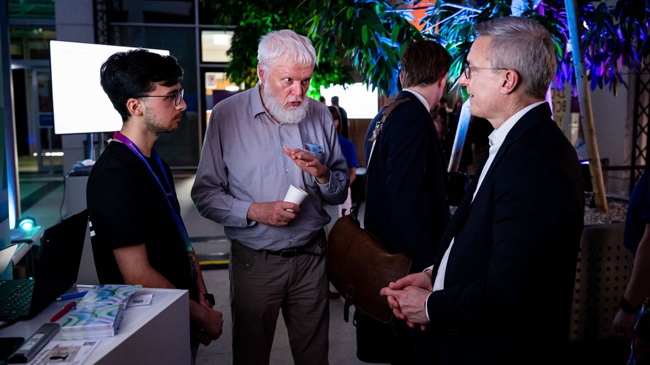 Minister Wildberger mit zwei männlichen Personen an einem Messestand
